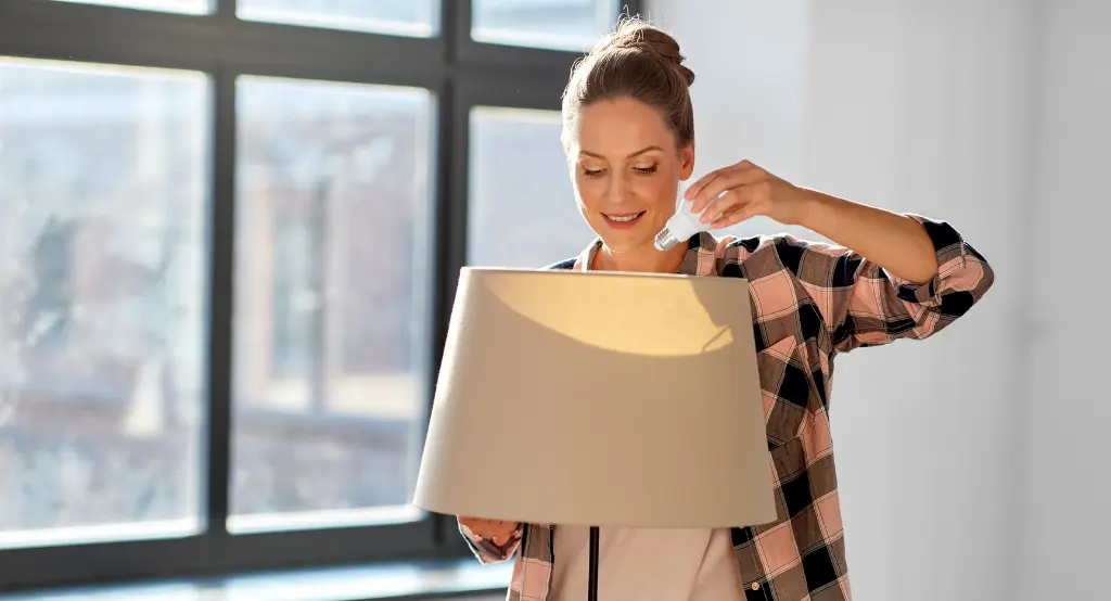 Mosolygó hölgy LED égőt teker az asztali lámpába
