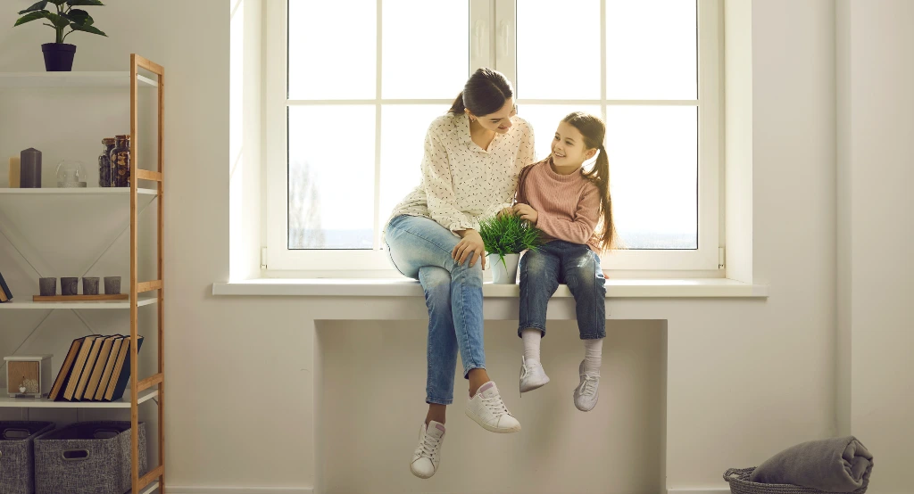 Anya és lánya az ablakpárkányon ülve beszélget