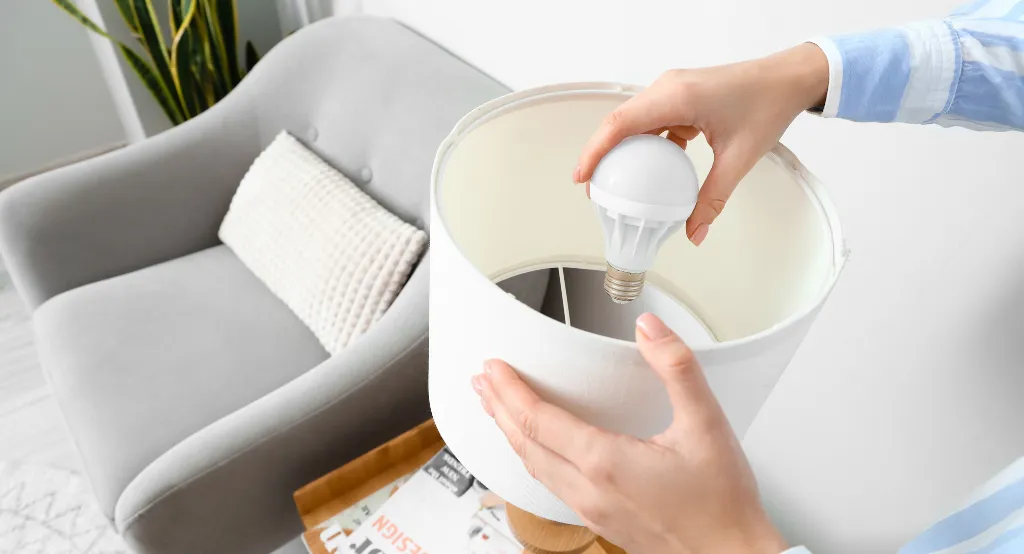 Egy férfi asztali lámpába LED fényforrást teker be