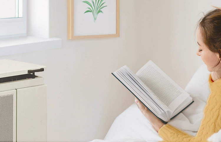 Konvektor mellett könyvet olvasó nő